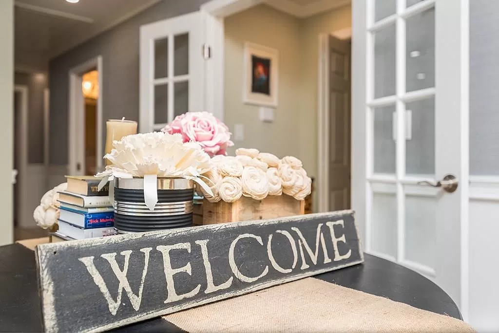 Welcome sign on table in front of flowers and books